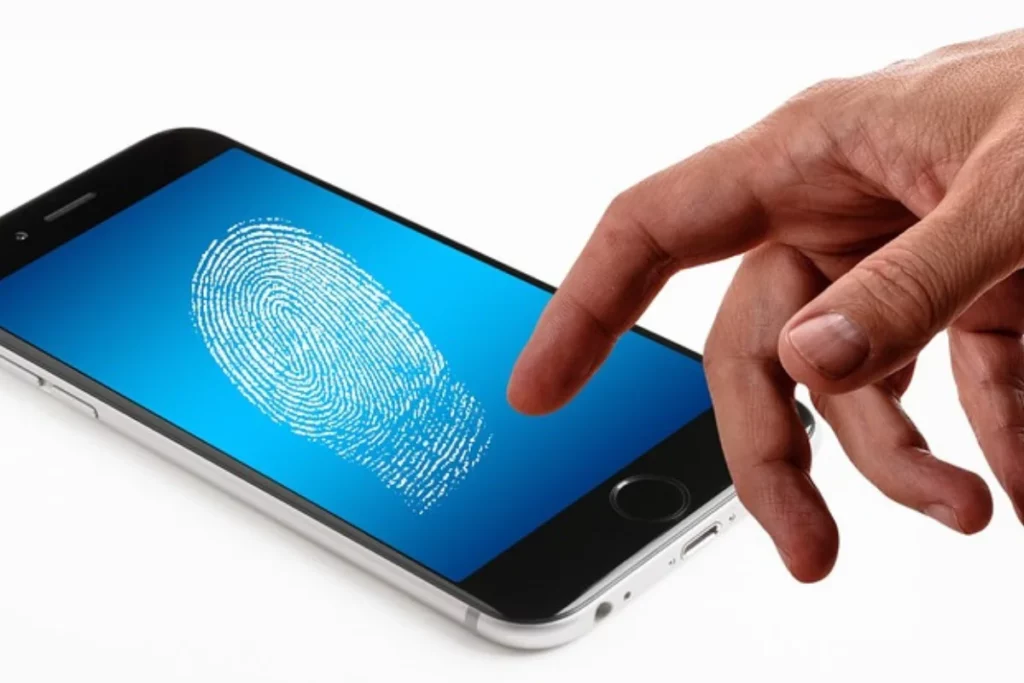 Mano con un celular que tiene una huella dactilar en la pantalla